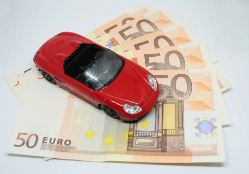 50ユーロ札が5枚扇状に並んでその上に赤いスポーツカーの模型が置いてある